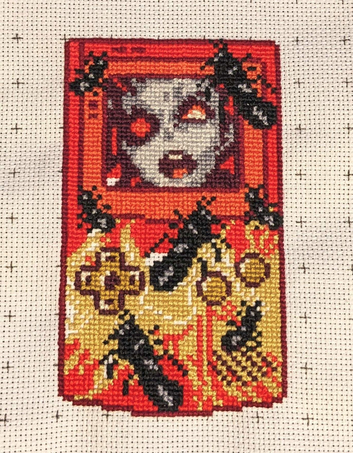 A cross stitch of a zombie infested GameBoy