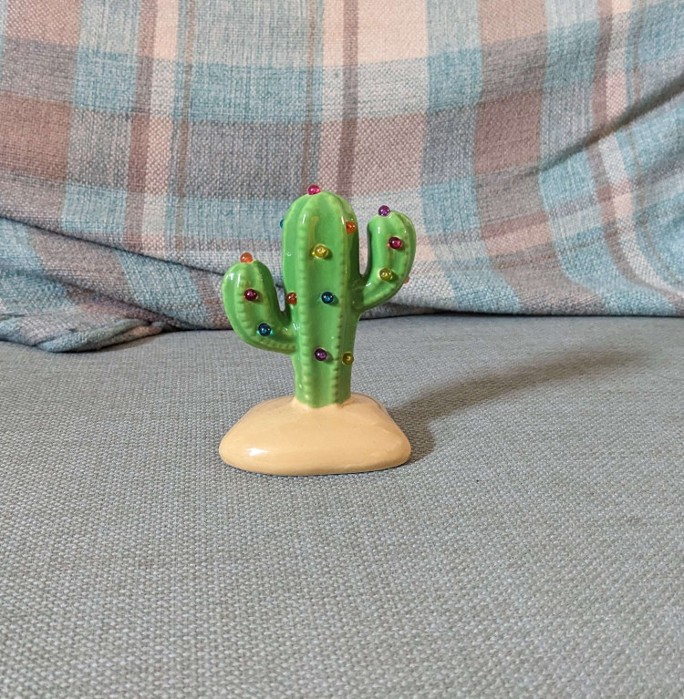 a very small green plastic cactus with a number of light-up gems attached to it. The gems are red, blue, and yellow